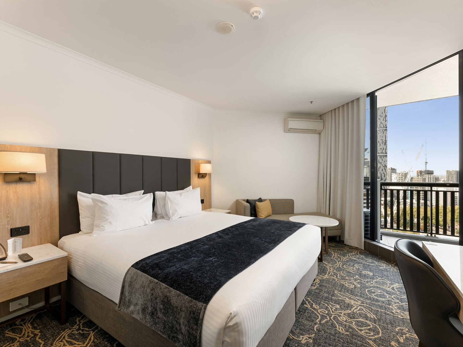 Bed with side lamp and work area in Deluxe King Balcony Room at Hotel Grand Chancellor Brisbane