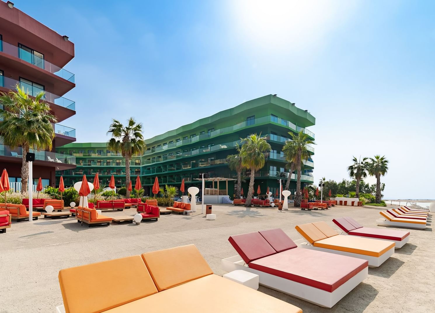 Hotel exterior, outdoor seating, palm trees & sun loungers facing the beach at Côte d'Azur Resort