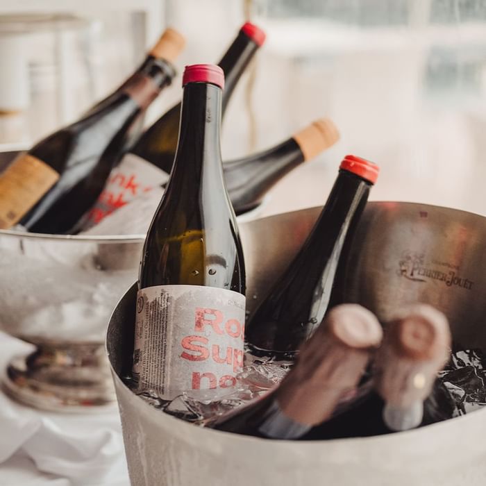 Bottiglie di vino in un secchio del ghiaccio con il ghiaccio, vicino ad un altro secchio del ghiaccio.