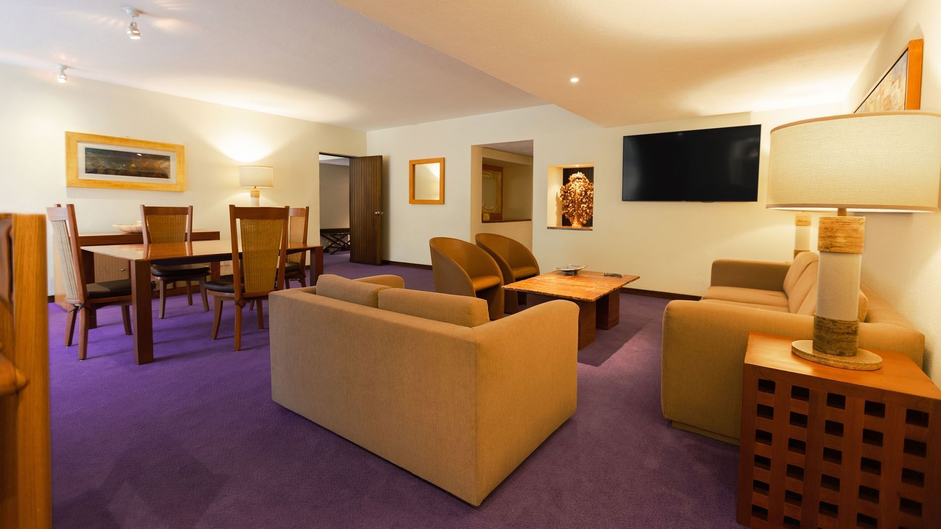 King Master Suite living area with tan sofas, a dining set, and purple carpeting at Camino Real Polanco Mexico
