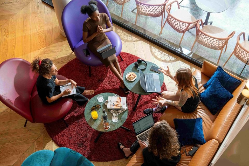 Gruppo di persone che lavora, fa coworking e socializza su poltrone colorate e tavolini in area lounge da Urban Hive Milano