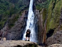 Un couple se tenant devant une cascade