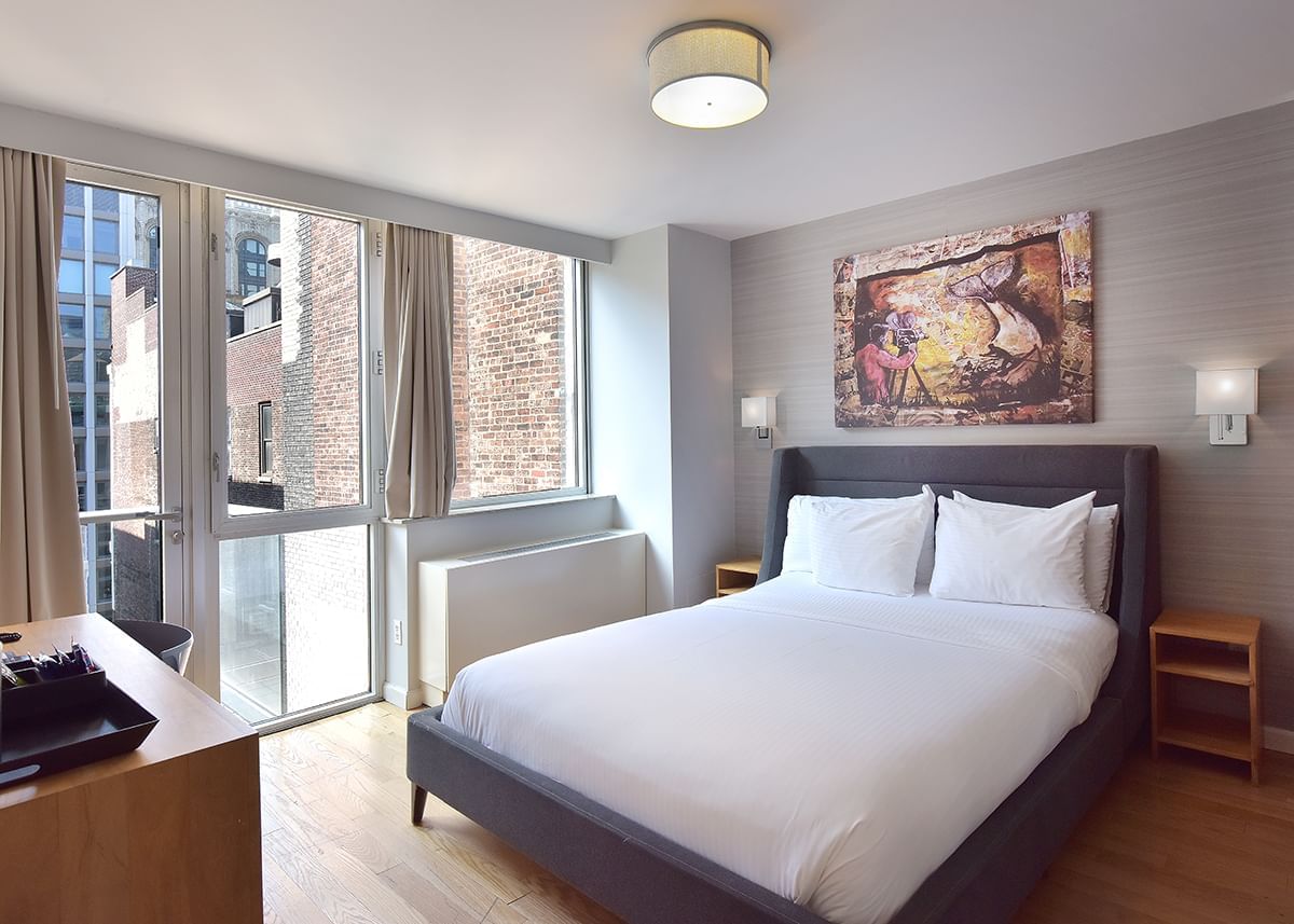 A hotel room with a large bed, desk, and window