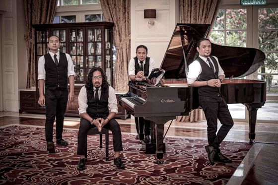 Live music performers posing by a piano in Verandah Bar at The Danna Langkawi