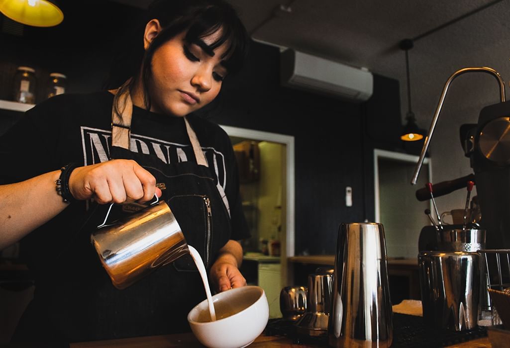 barista pours milk into espresso