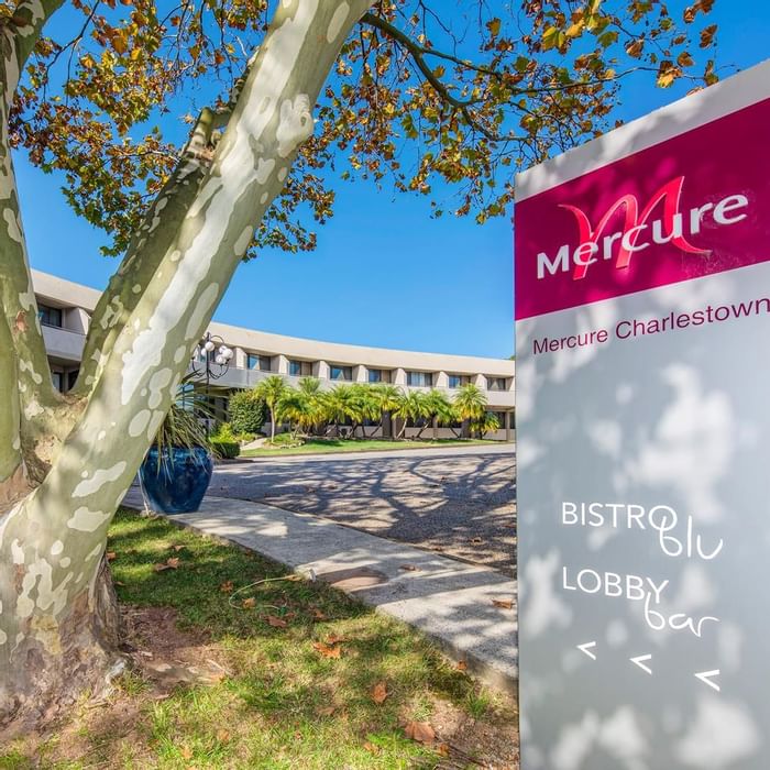 Mercure Charlestown signboard featuring text for Bistro Blu and Lobby Bar, surrounded by greenery at Mercure Charlestown