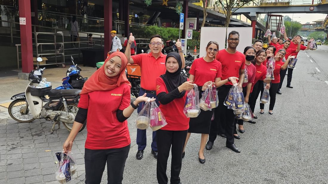 A group of people in red shirts holding a bag with foods at Sunway Putra Hotel