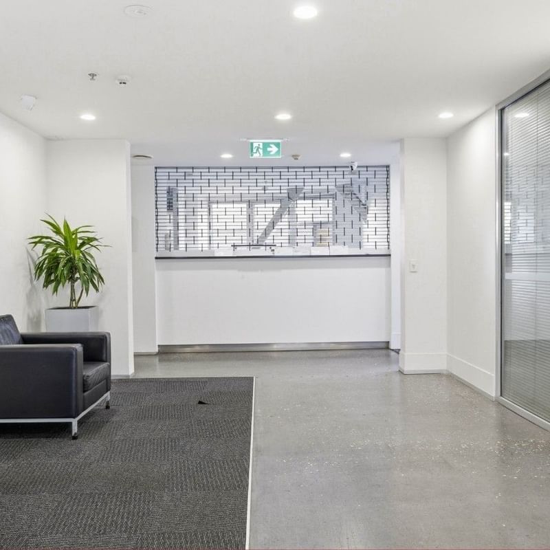 Black leather chairs and a potted plant in the hallway at Student Living Auckland – Anzac.