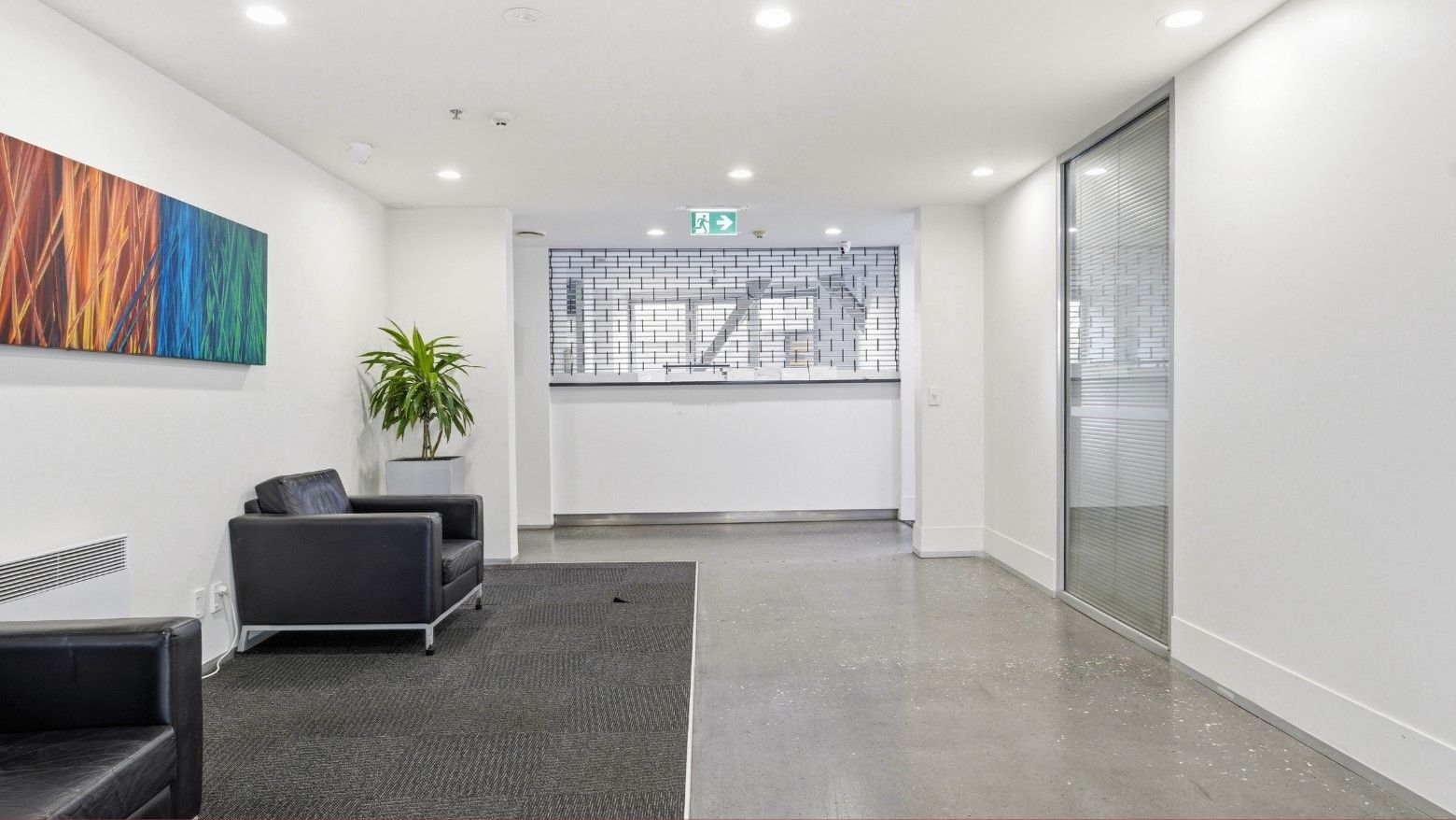 Black leather chairs and a potted plant in the hallway at Student Living Auckland – Anzac.