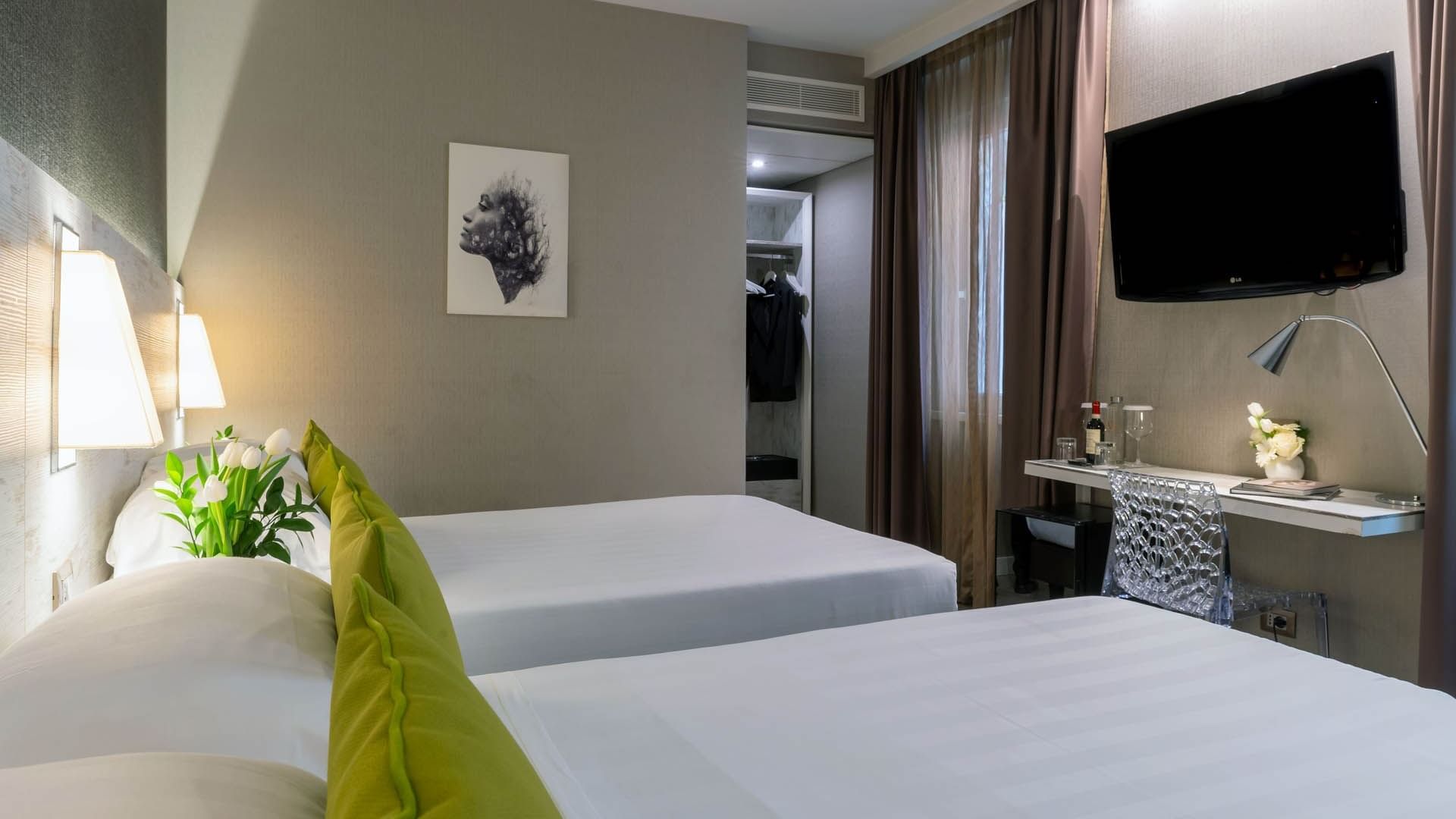 Modern Family Apartment with two green-accented beds, a desk, a TV, and a curtained window at The Guardian Hotel