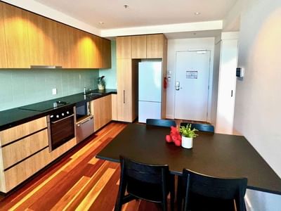 A dining area with a table and chairs in a modern apartment at UniLodge at Curtin University - Zamia Apartments.