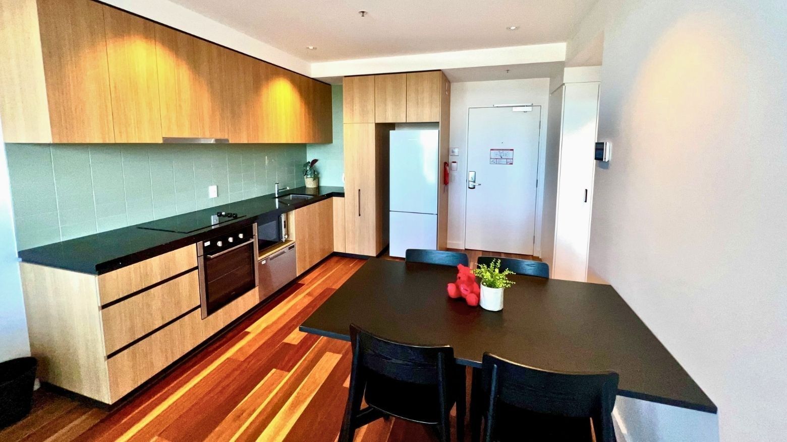 A dining area with a table and chairs in a modern apartment at UniLodge at Curtin University - Zamia Apartments.