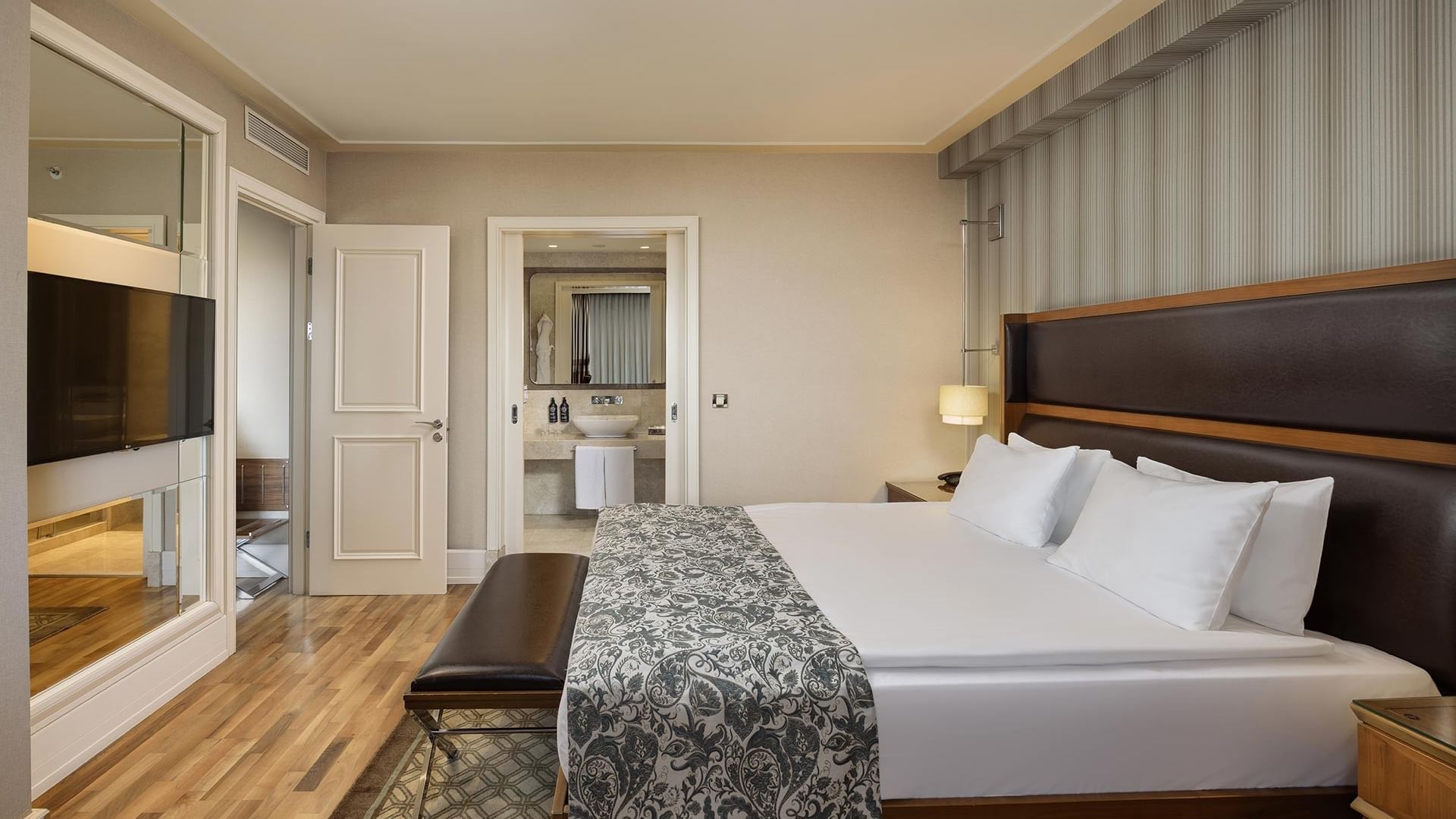 A luxurious suite with a large bed, balcony, and modern decor at Titanic City Taksim.