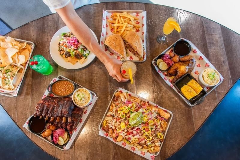 Overhead view of a table filled with ribs, burgers, nachos, and colorful cocktails at Shangri-La Resort and Golf Club