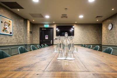 Stylish Dame Judi Dench room at The Met Hotel Leeds, England, with a wooden table, dark teal chairs, and a modern design