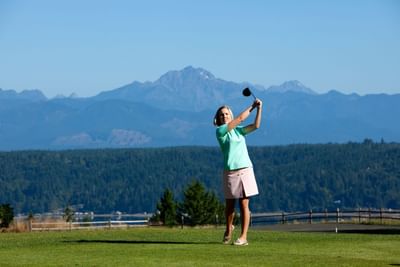 Woman playing golf on a course with mountains in the background near Alderbrook Resort & Spa