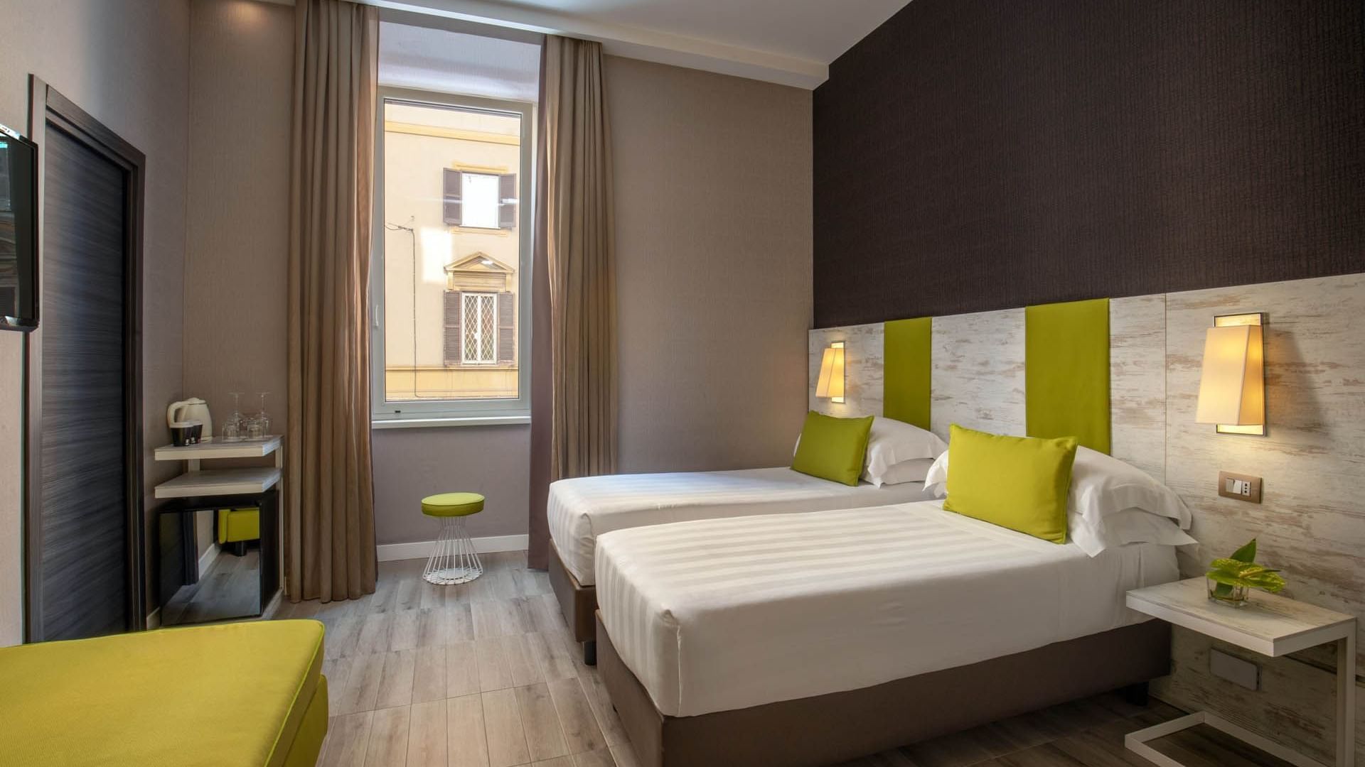 Modern Superior Room at The Guardian Hotel with two beds, green accents, a side table, and a window with city views