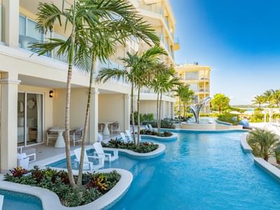 Luxurious swimming pool curving around tropical plants and palm trees at Windsong Resort On The Reef