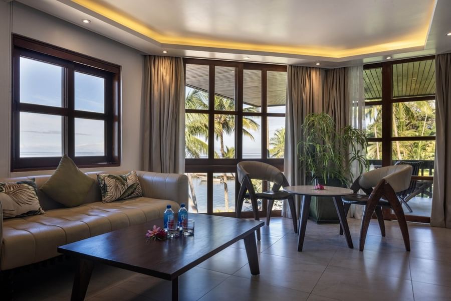 Modern chairs by a round table under warm ceiling lights near a large plant in Warwick Suite at Warwick Fiji Resort and Spa