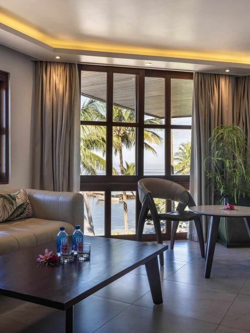 Beige sofa by a wood table under warm ceiling lights near a leafy plant in Warwick Suites at Warwick Fiji Resort and Spa