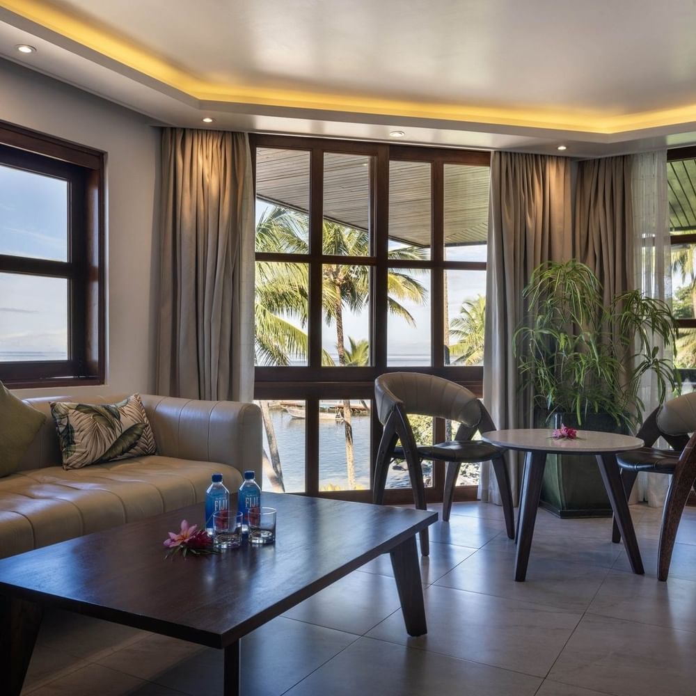 Beige sofa by a wood table under warm ceiling lights near a leafy plant in Warwick Suites at Warwick Fiji Resort and Spa