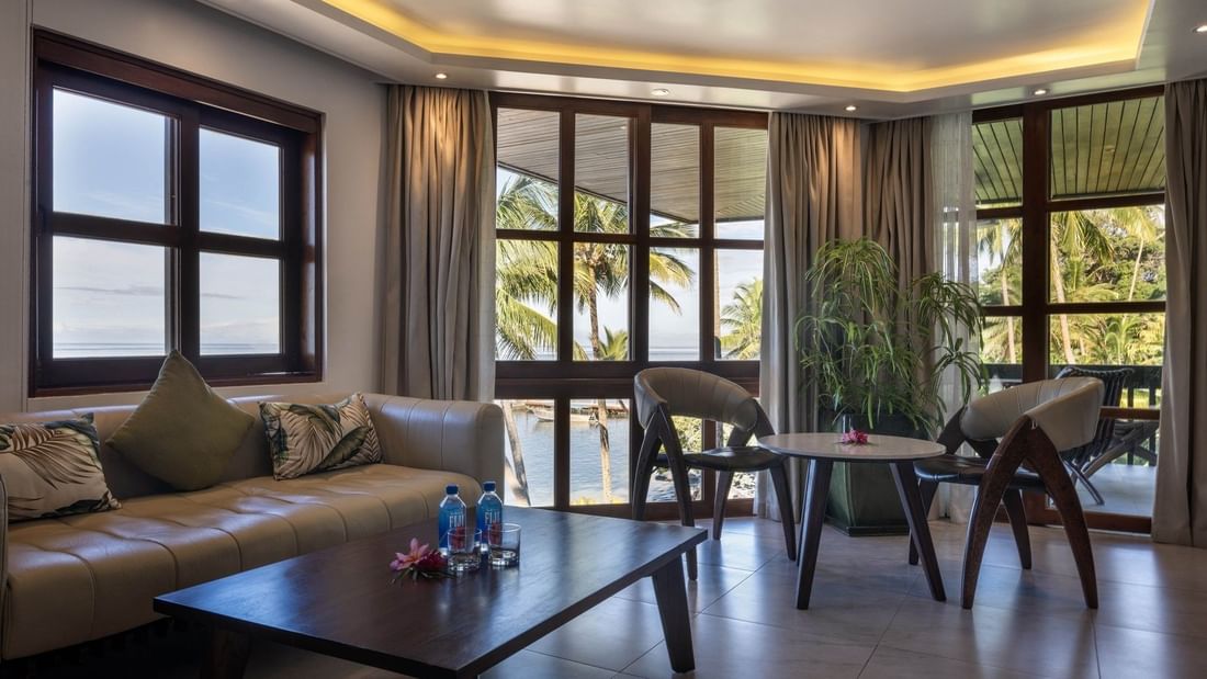 Beige sofa by a wood table under warm ceiling lights near a leafy plant in Warwick Suites at Warwick Fiji Resort and Spa