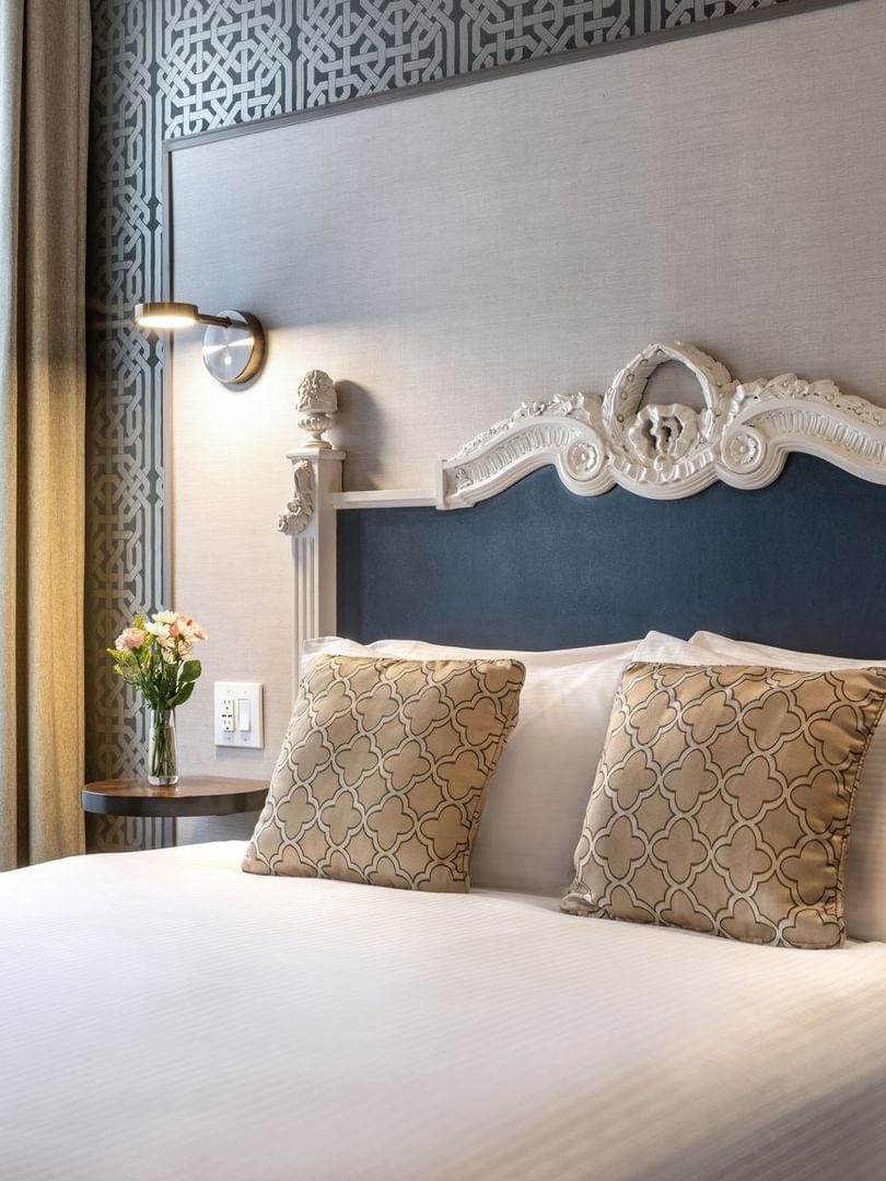 Ornate white headboard by patterned wallpaper in Accessible Executive Front Suite at Warwick San Francisco