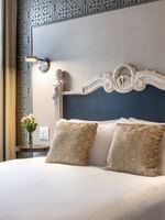 Ornate white headboard by patterned wallpaper in Accessible Executive Front Suite at Warwick San Francisco