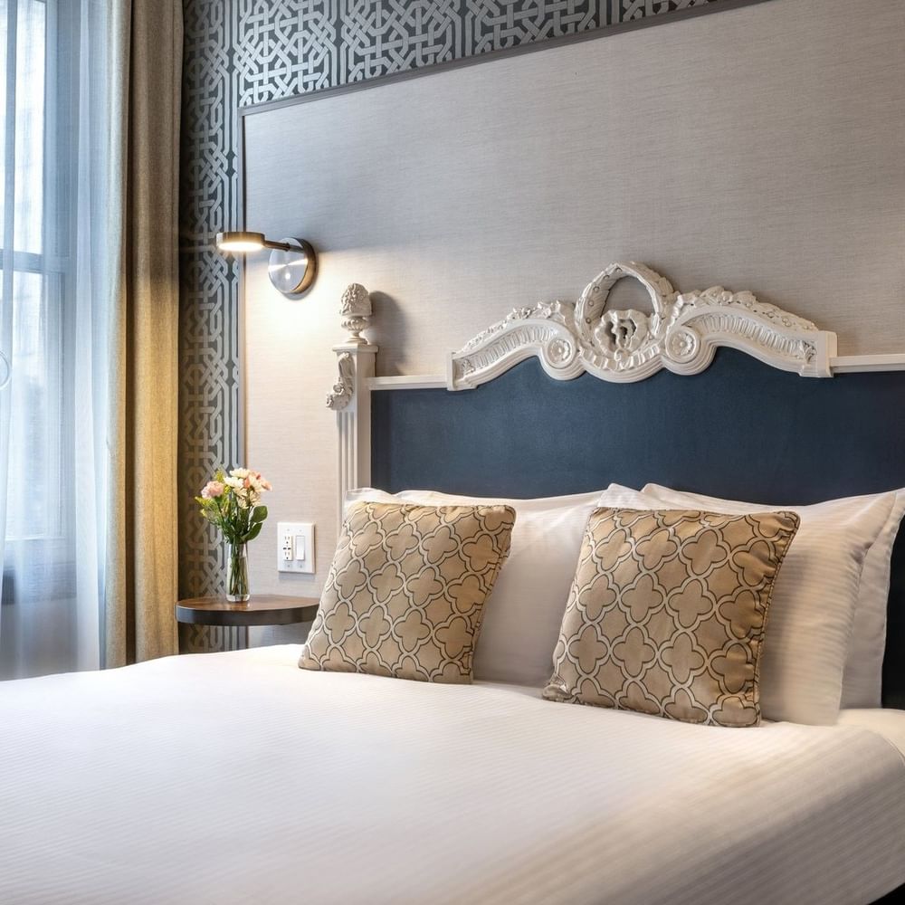 Ornate white headboard by patterned wallpaper in Accessible Executive Front Suite at Warwick San Francisco