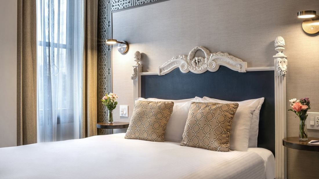 Ornate white headboard by patterned wallpaper in Accessible Executive Front Suite at Warwick San Francisco