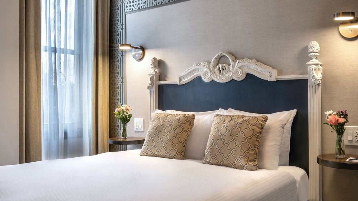 Ornate white headboard by patterned wallpaper in Accessible Executive Front Suite at Warwick San Francisco