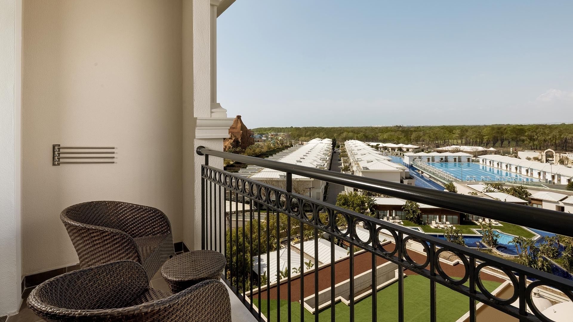 Balcony view of Standard Room with chairs and pool views at Titanic Deluxe Golf Belek in Antalya.