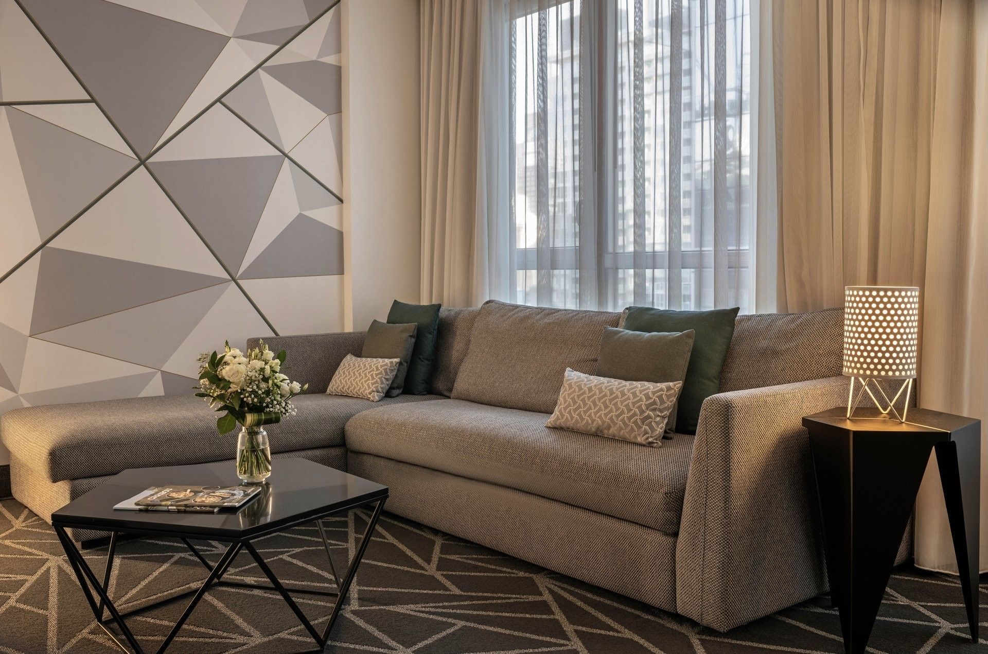 Grey L-shaped sofa & black coffee table by window at Warwick Le Crystal Montreal