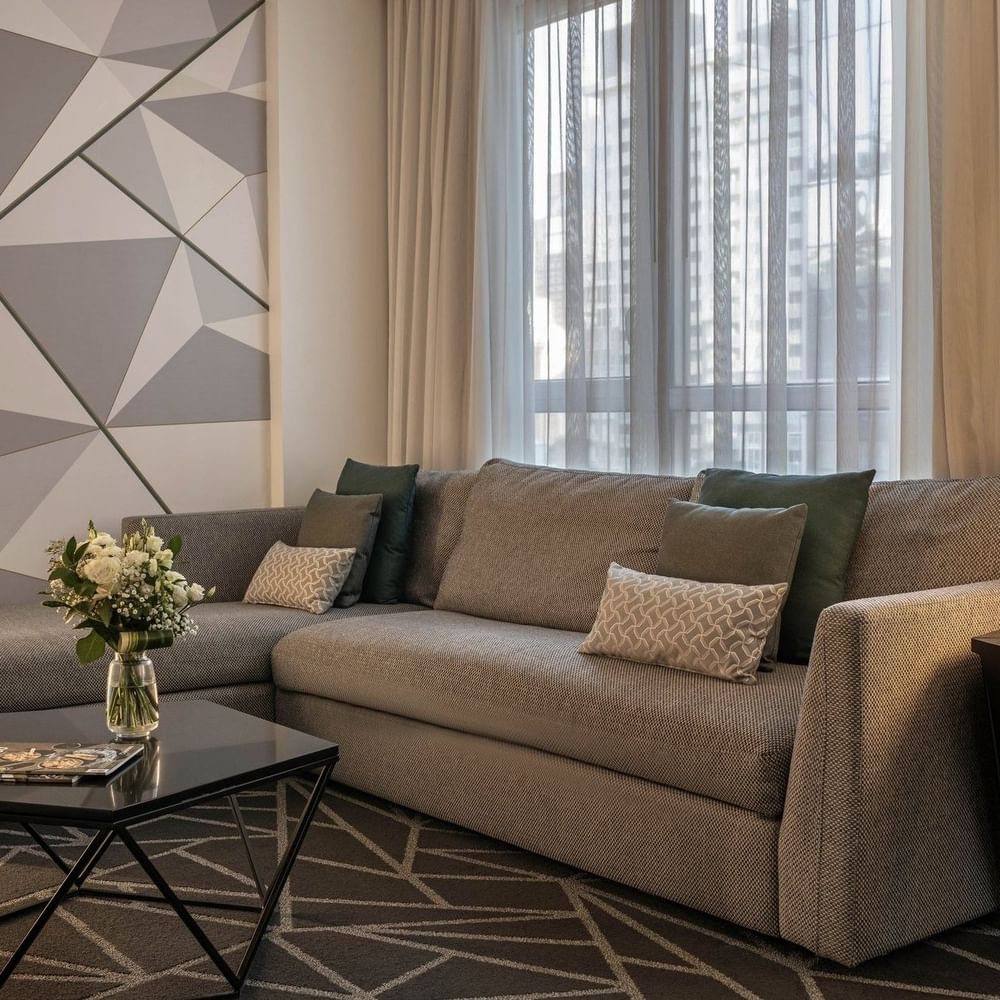 Junior Suite living area with plush sofa & coffee table near window at Warwick Le Crystal Montreal