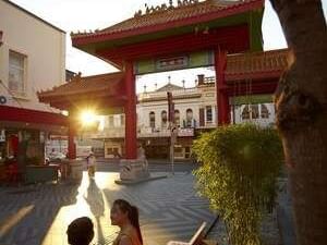 Brisbane's Chinatown at sunset, with people sitting in the foreground near The Sebel Brisbane