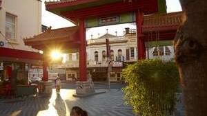 Brisbane's Chinatown at sunset, with people sitting in the foreground near The Sebel Brisbane
