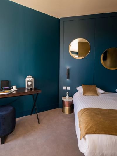 Chambre élégante avec lit, bureau, miroirs décoratifs et éclairage chaleureux.