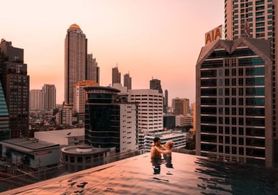 Couple posing in the infinity swimming pool during sunset at Eastin Hotels