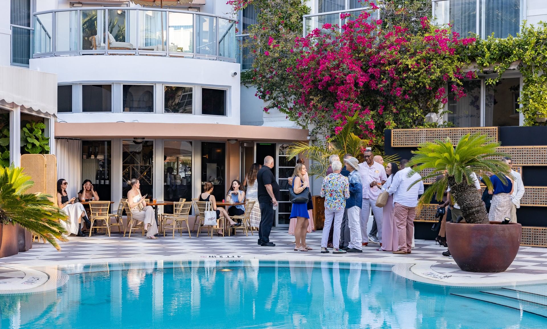 A group of people gathered around a pool area with a building in the background