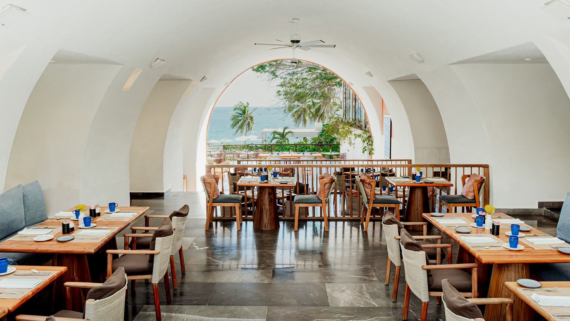 Dining area with plush seating and a large white arch, overlooking the ocean in Chez Binni at Camino Real Zaashila Huatulco