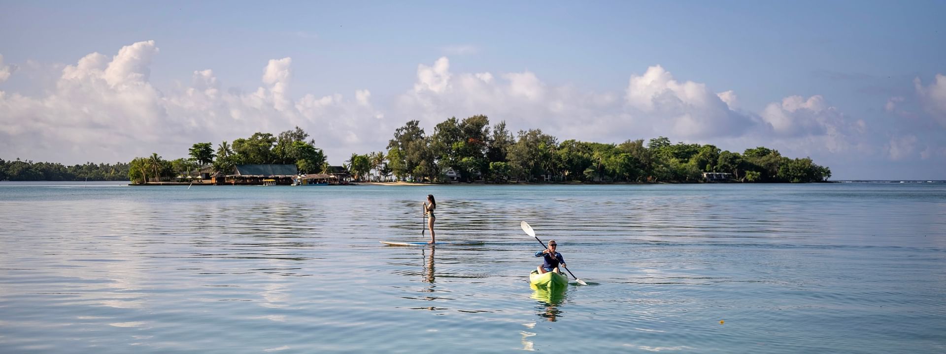 Two people enjoying kayaking and paddleboarding on tranquil waters at Warwick Le Lagon in Efate