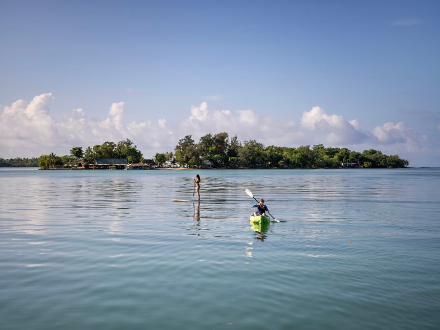 Two people enjoying kayaking and paddleboarding on tranquil waters at Warwick Le Lagon in Efate