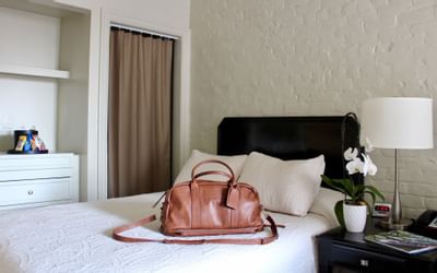 A traveling bag on a bed in Guestroom at La Galerie Hotel