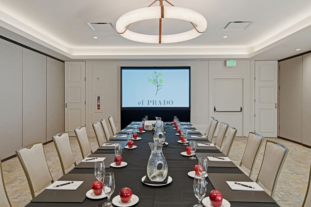 meeting room set up at el PRADO with a screen at the end of the table reading el PRADO with a yellow flower