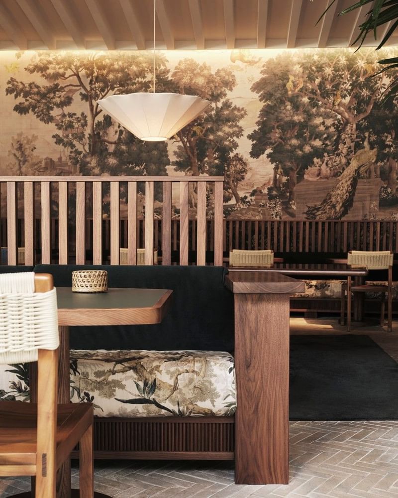 Modern hotel restaurant interior with wooden furniture, large landscape mural, and contemporary lighting design