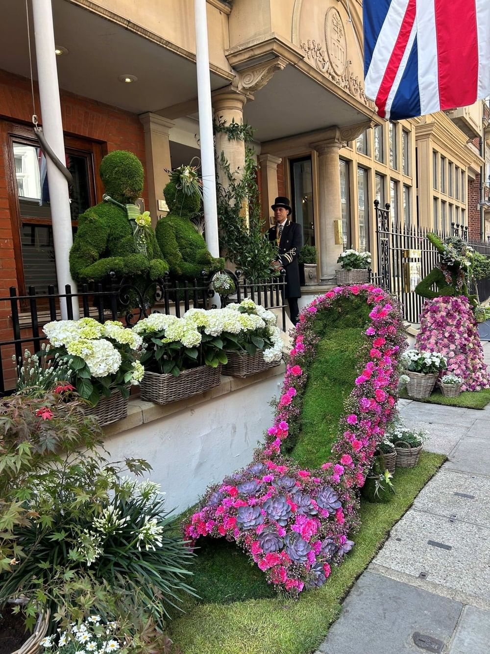 Man in uniform standing in front of floral display at Chelsea Flower Show 2026.