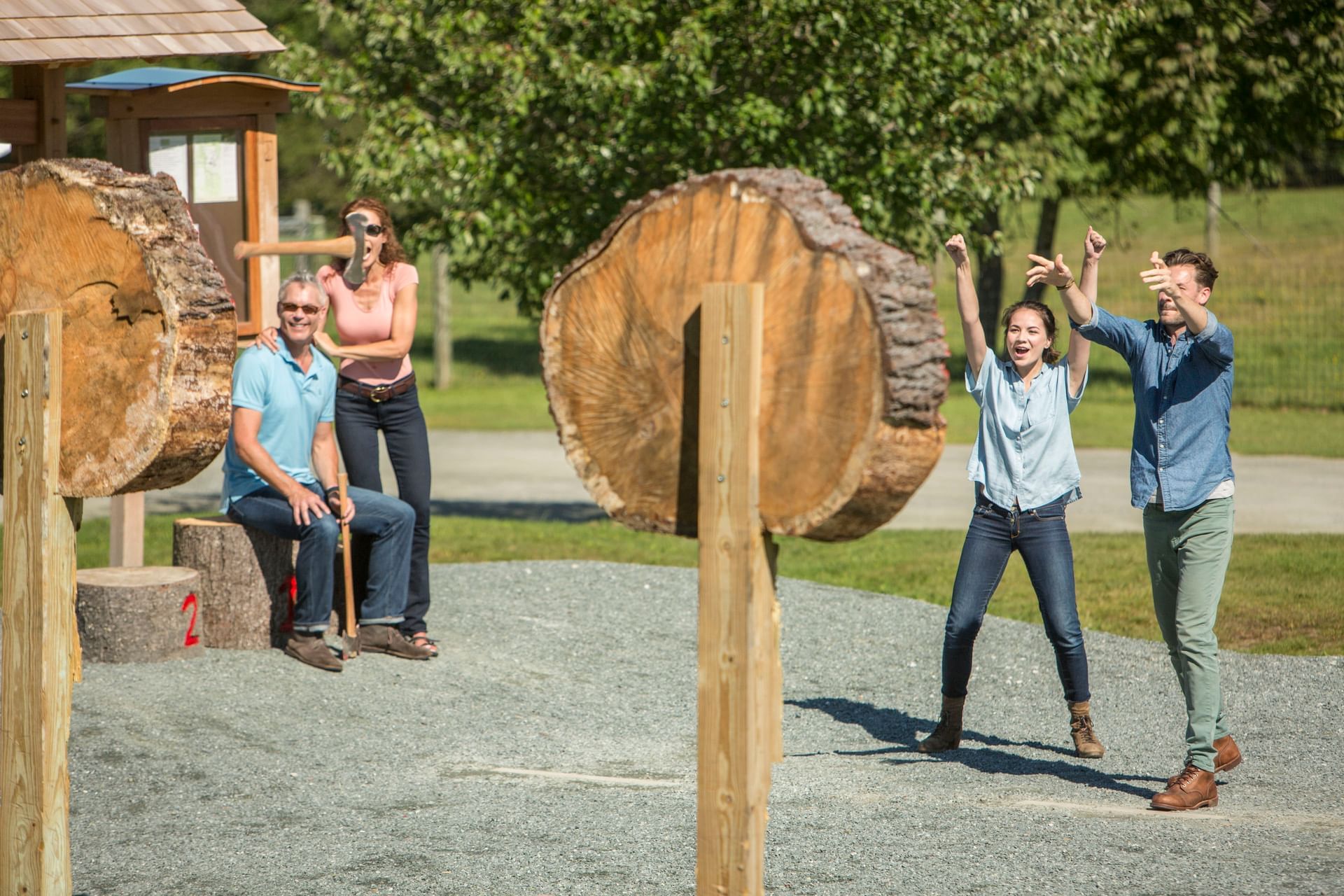 Group cheering by wooden target logs on stakes, near a shelter and trees at Mountain View Grand Resort & Spa