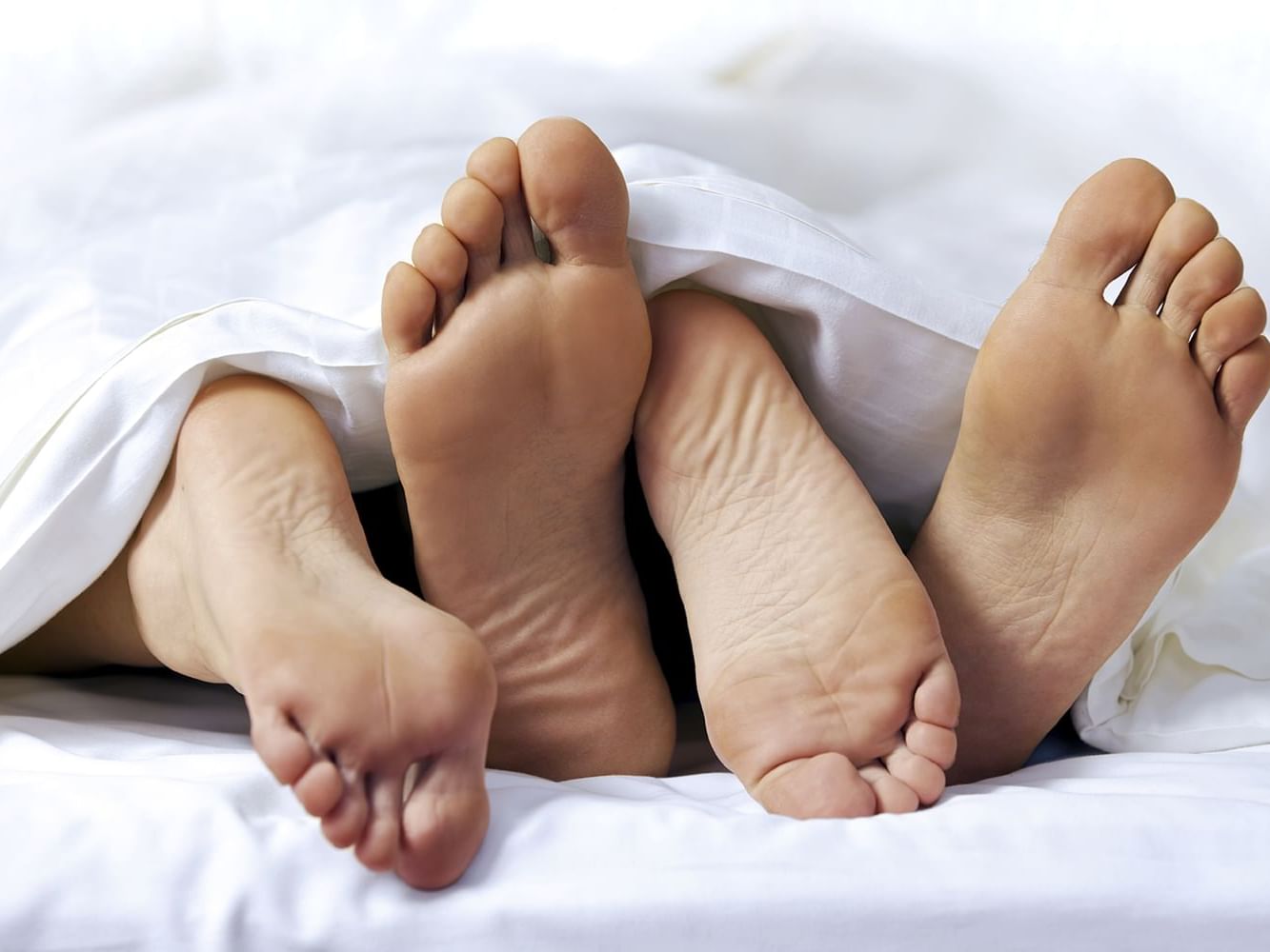 Close-up of the feet of a couple on the bed at The Godfrey