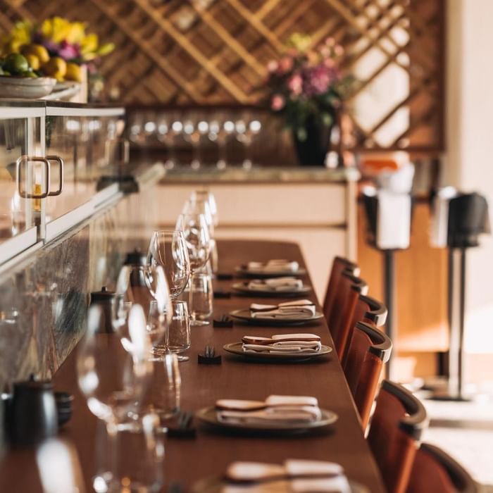 Eleganter Esstisch mit Gläsern und Tellern, umgeben von Stühlen in einem stilvollen Restaurant.