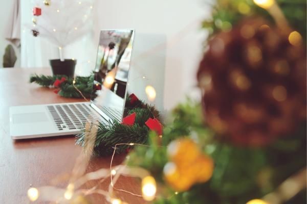 Laptop with festive decor around after person following up with team on the corporate Christmas party